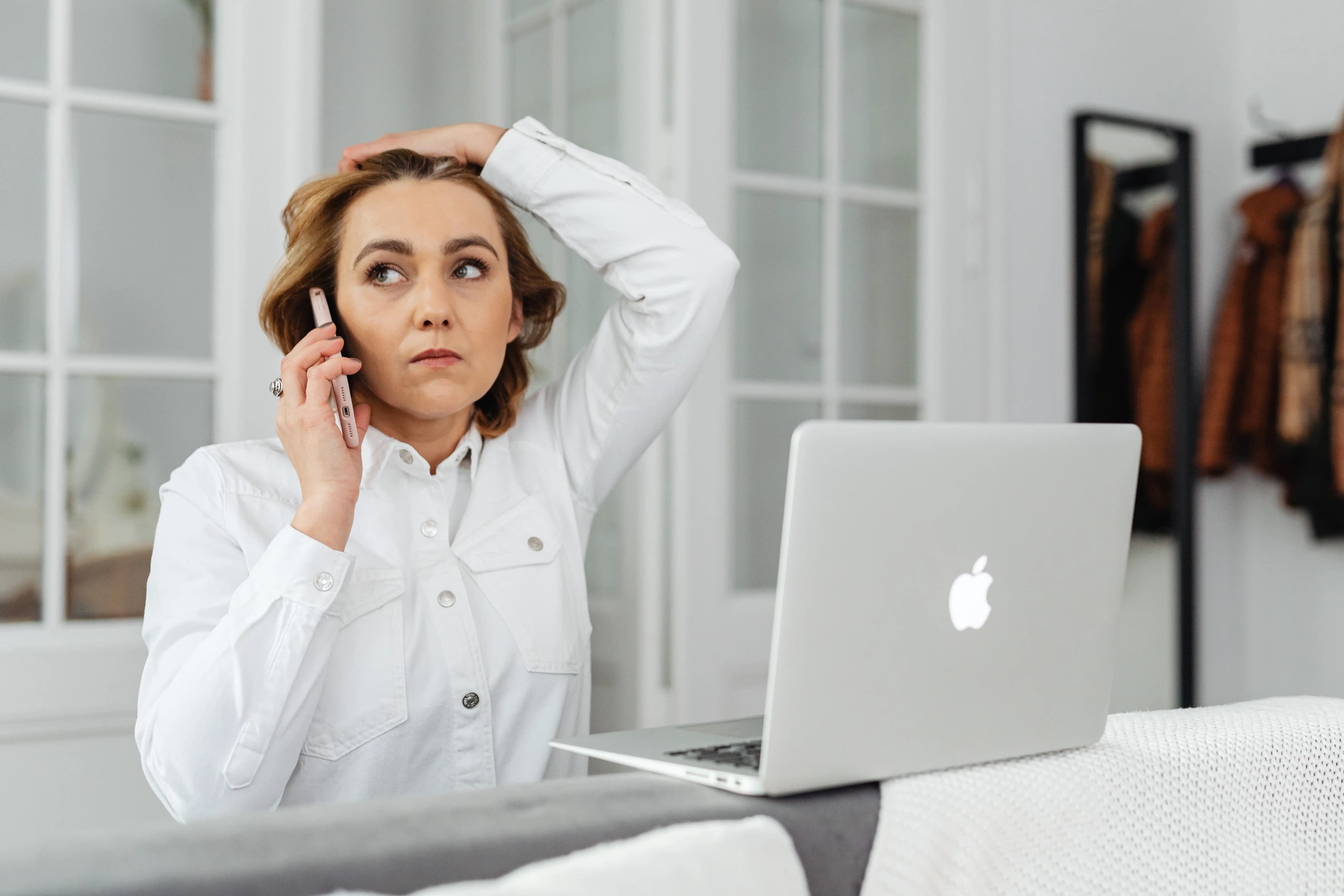 Worried small business owner on a phone call about a company filing issue, sitting at her laptop