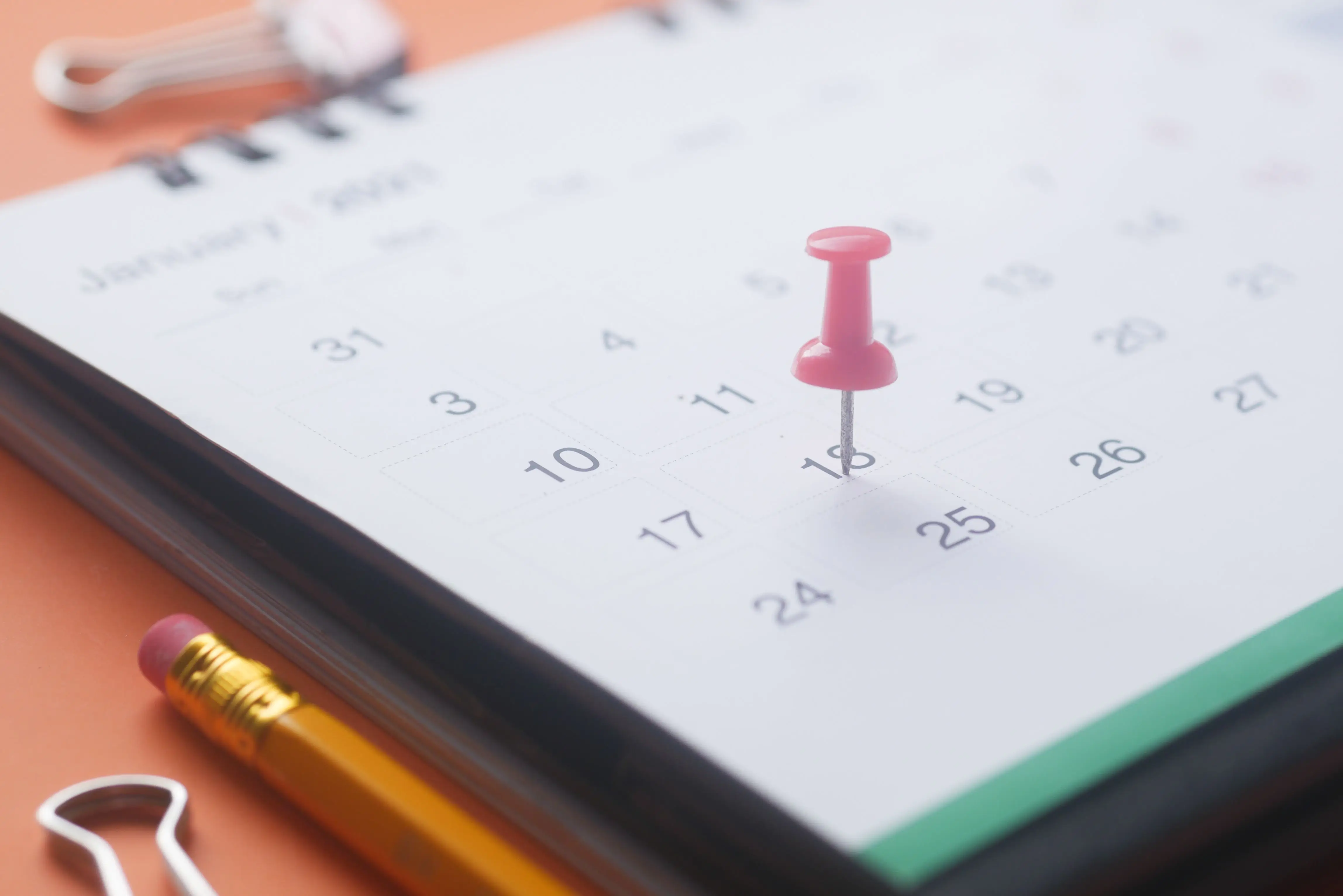 Desk calendar with a pink pushpin marking a filing deadline for a Washington LLC's annual report